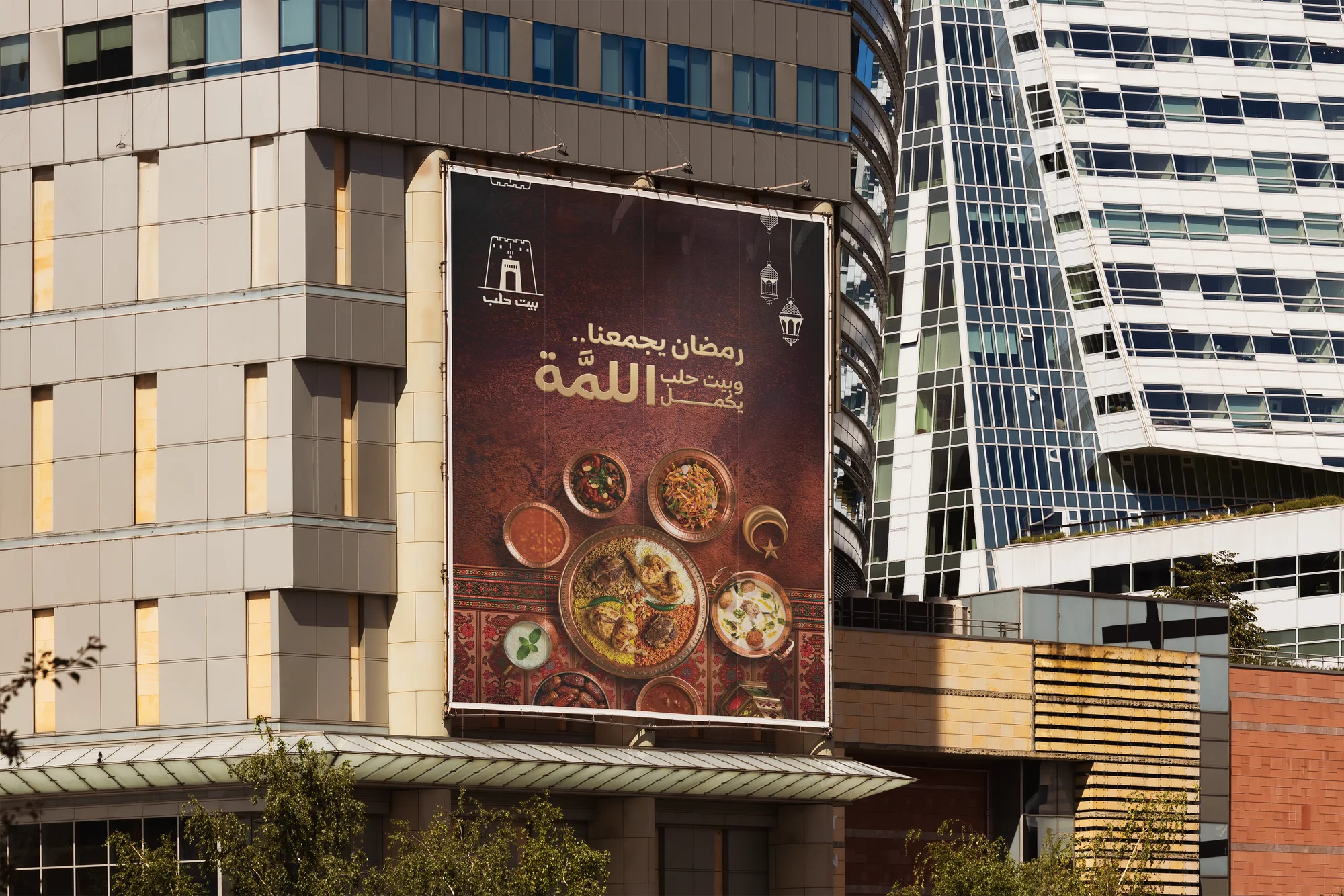 Large Beit Halab Ramadan flex hung on a city building: copper iftar dishes under the line Ramadan brings us together
